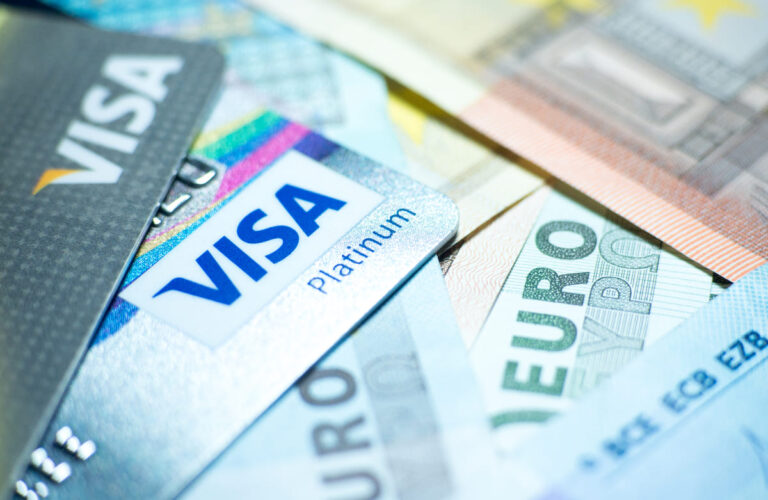 Cartões da Visa junto a diferentes moedas e dinheiro