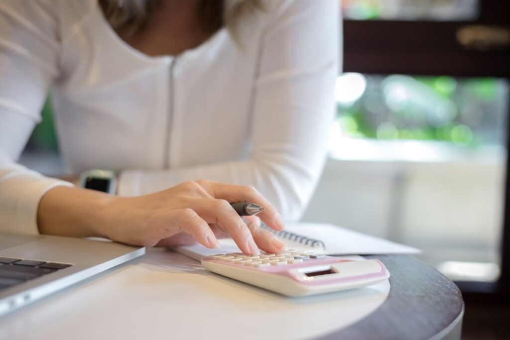 Mão de mulher calculando em uma calculadora branca