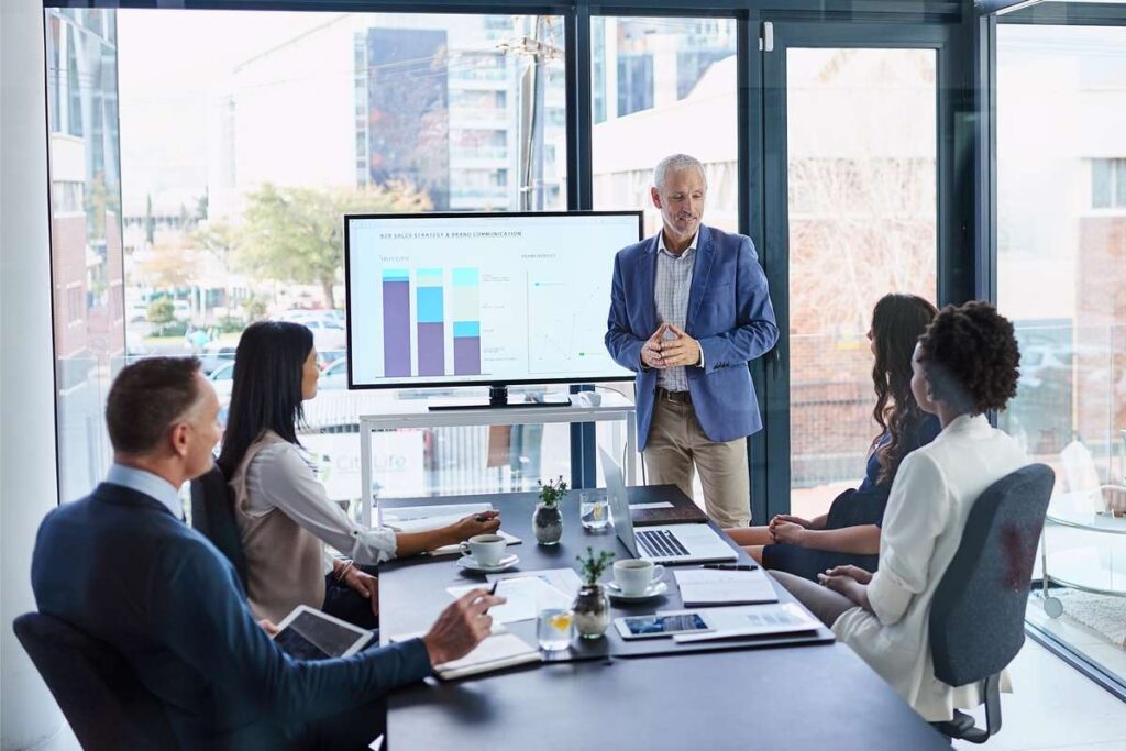 Empresário apresentando os resultados da economia de escala interna da empresa a sua equipe. 