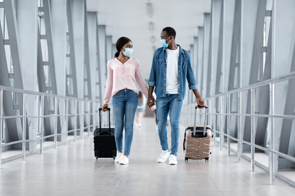 Jovem casal de mãos dadas e máscara contra a covid, no aeroporto