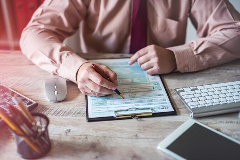 Mãos de homem preenchendo formulário em um escritório.