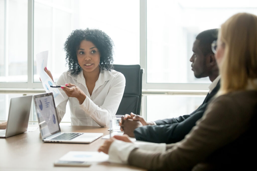 Três pessoas em reunião esclarecendo dúvidas sobre uma proposta comercial.