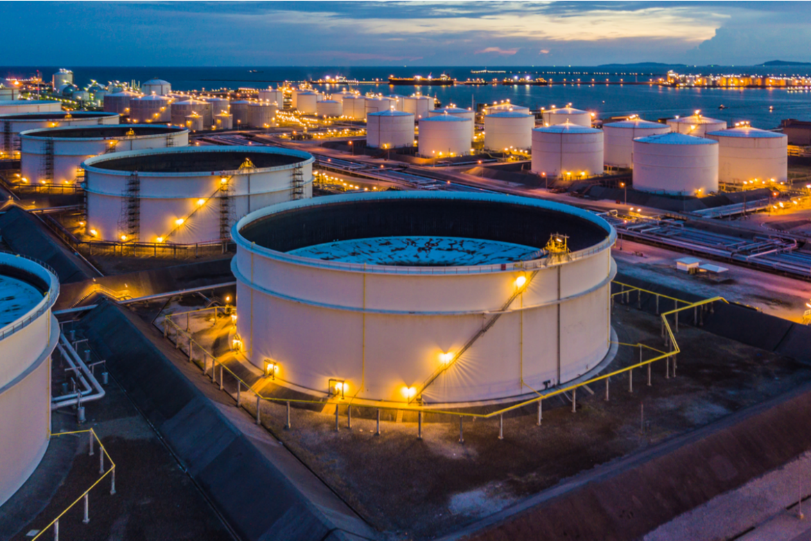 Foto de barris de petróleo em fim de tarde com luzes acesas