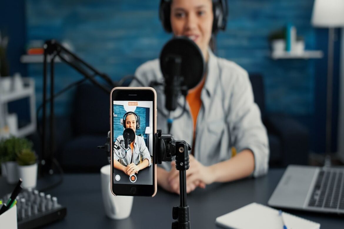 Influencer fazendo live no Instagram com o seu celular em um estúdio.