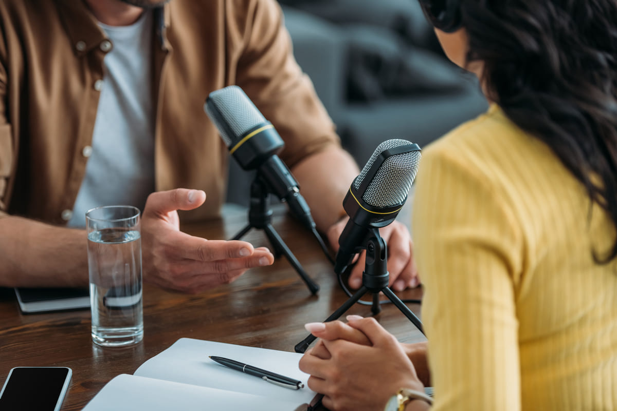 Mulher explicando para um homem como fazer um podcast.