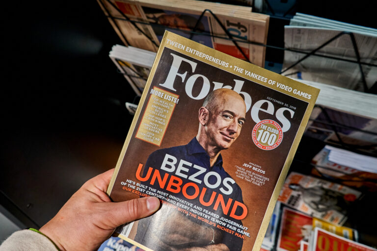 pessoa segurando a revista da Forbes do Jeff Bezos, o segundo homem mais rico do mundo em 2022