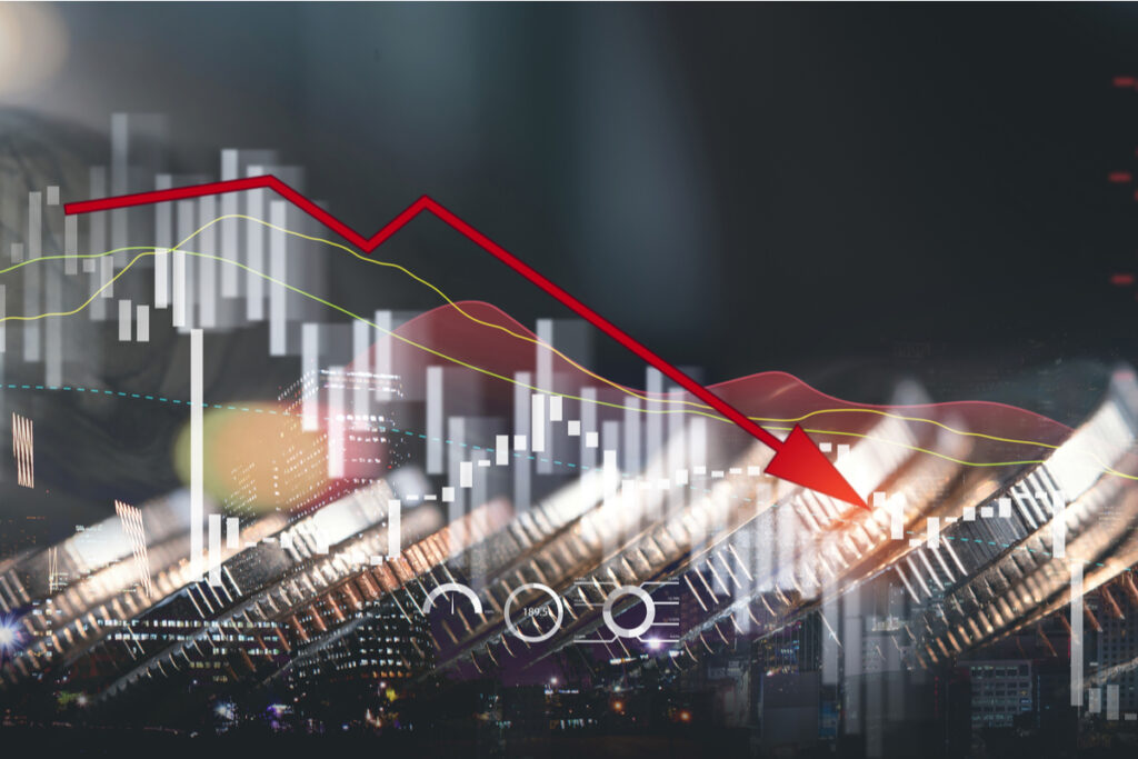 gráfico, moedas e seta para baixo destacando a queda da economia