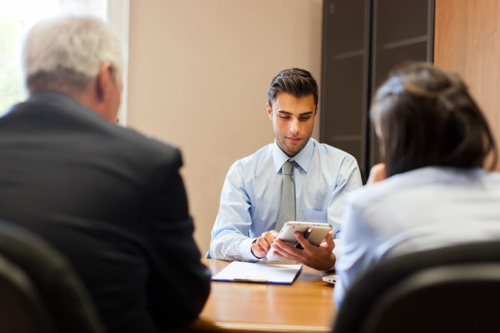 Três pessoas sentadas em uma mesa  verificando o método venture capital.