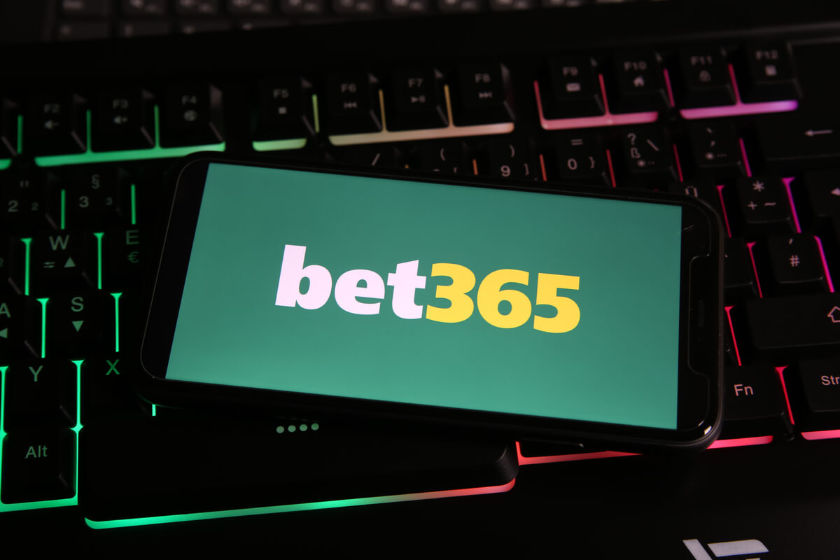 Um celular com o logotipo do Bet365 na tela, sobre um teclado luminoso