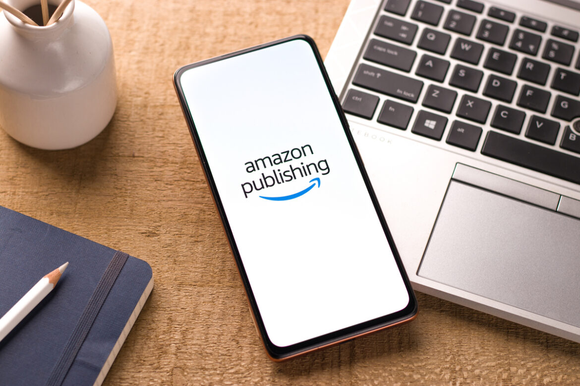 Foto de celular com tela do Amazon Publishing aberto em cima de um notebook