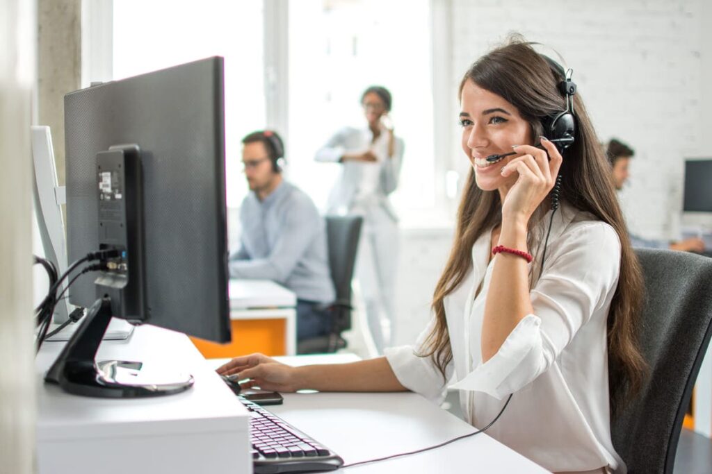 Mulher falando ao telefone com um fone para explicar como implementar customer success.