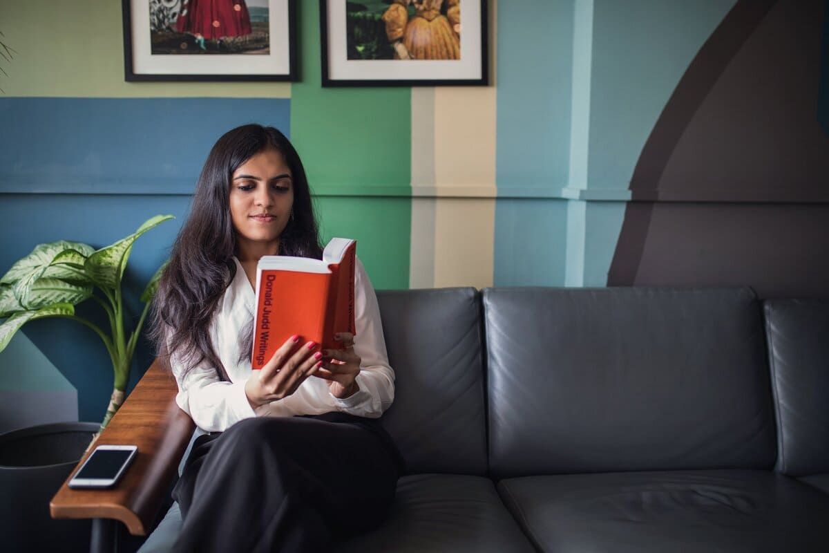 Mulher sentada no sofá lendo um livro