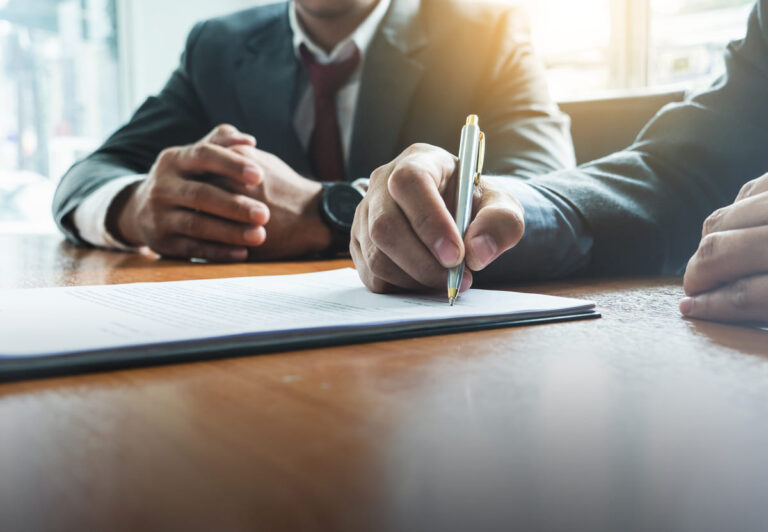 Homens em uma mesa assinando documentos