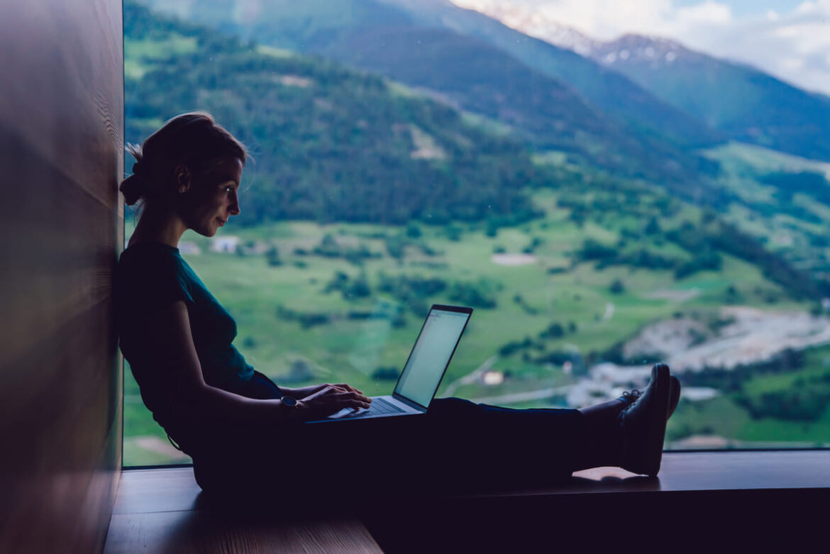 Mulher olhando computador para ver informações sobre o visto para nômade digital em Portugal.