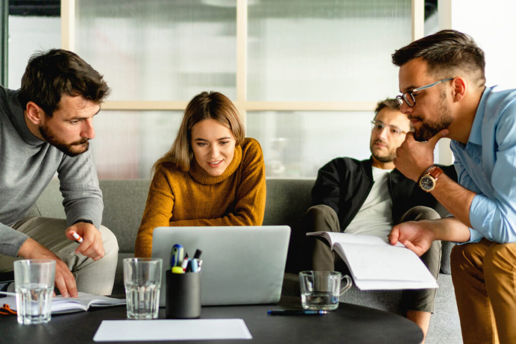 Pessoas olhando um computador e tentando resolver um problema em um coworking.