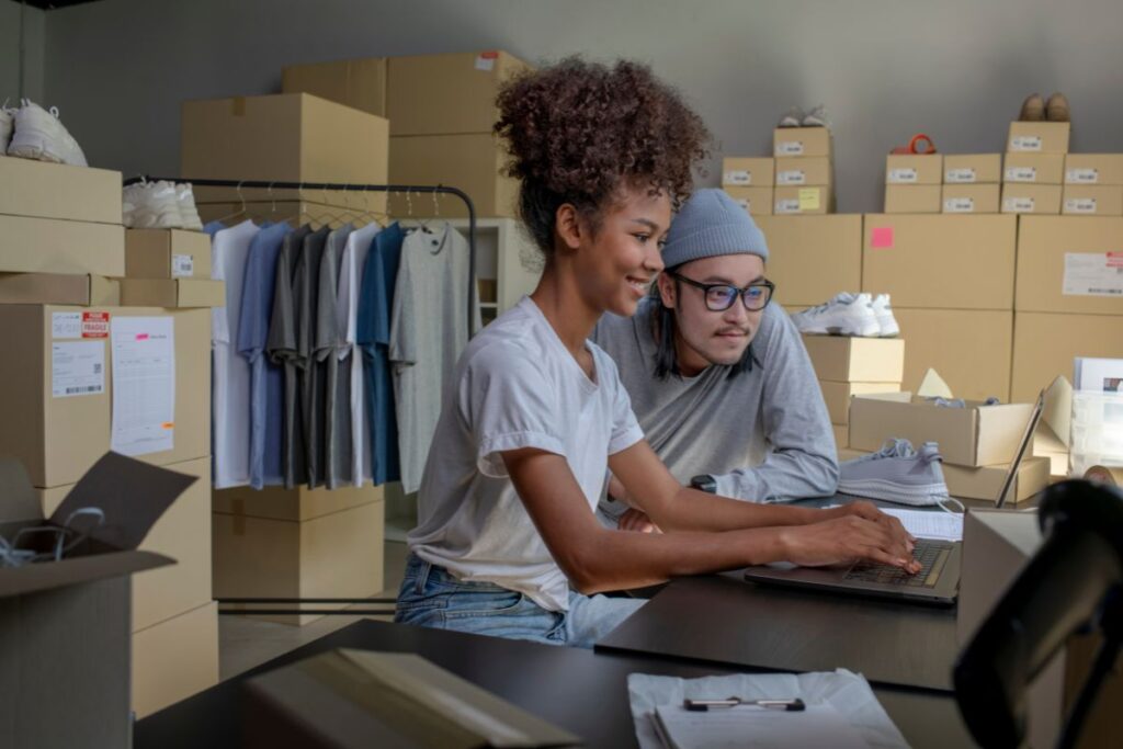 Casal importando produtos de vestuário por marketplaces. 