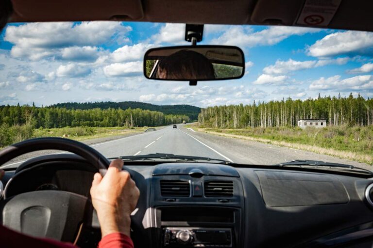 Close-up de mãos segurando o volante e dirigindo em uma estrada