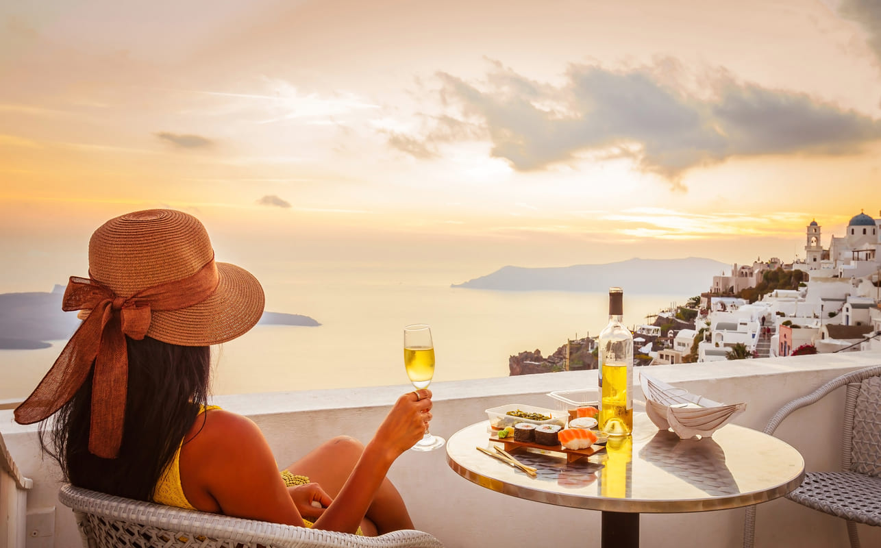 Uma mulher branca observando o pôr do sol em Santorini