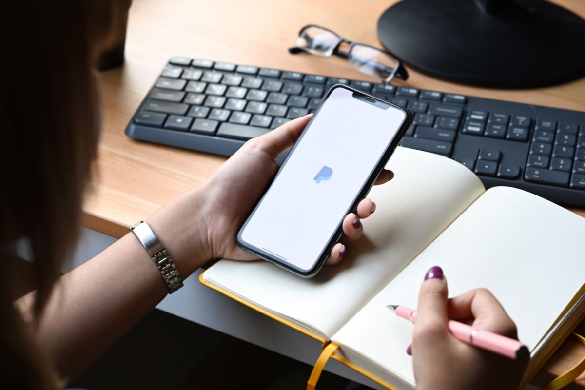 Mulher com smartphone com app do PayPal aprendendo como sacar dinheiro.