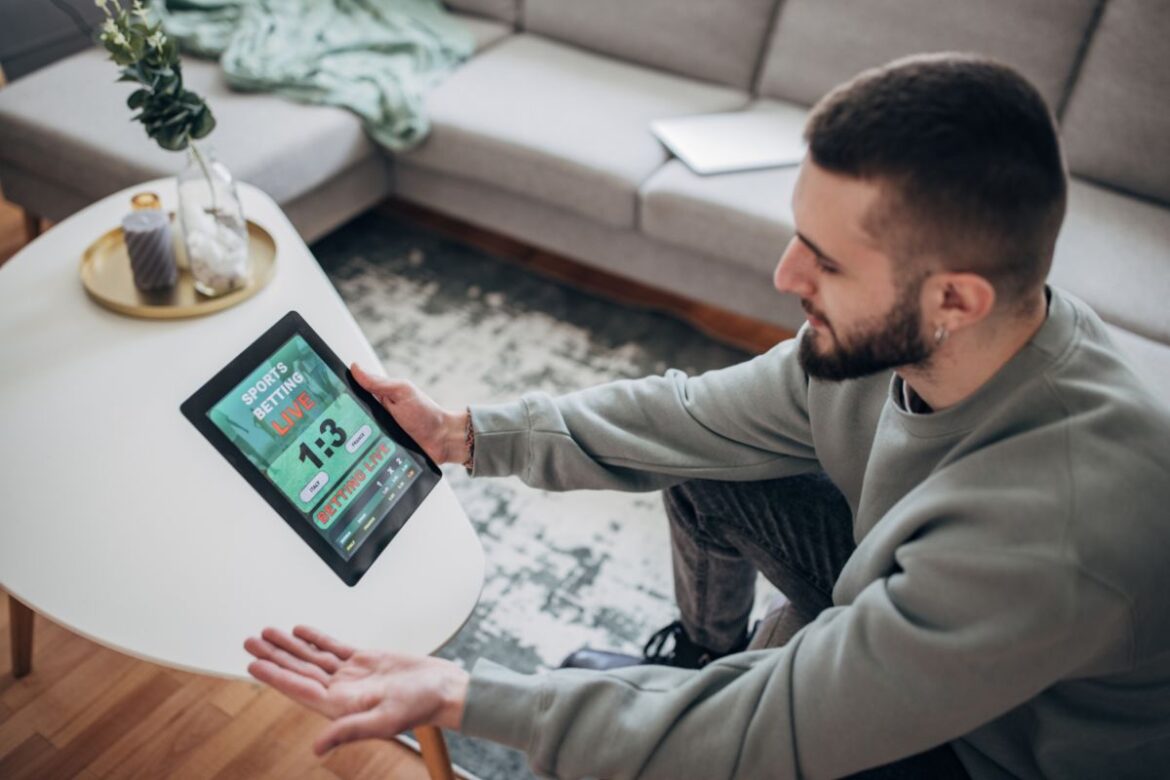 Homem segurando tablet com site de apostas aberto.