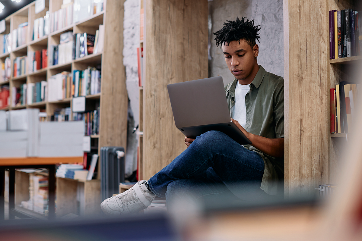 Um jovem com seu notebook em uma biblioteca