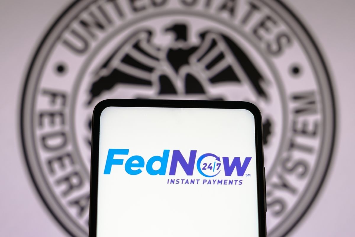 Logo do FedNow na tela do smartphone e símbolo dos Estados Unidos ao fundo.